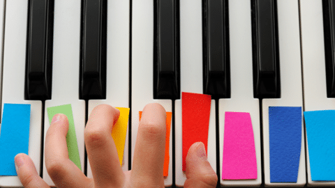 Closeup of Kid's hands playing color coded piano keys