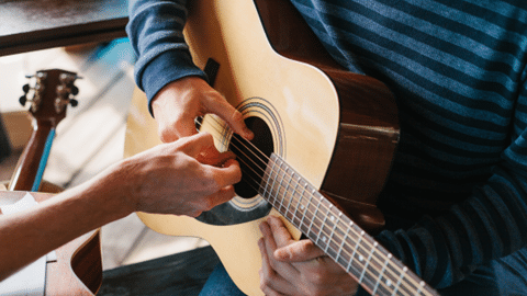 Guided hands on acoustic guitar